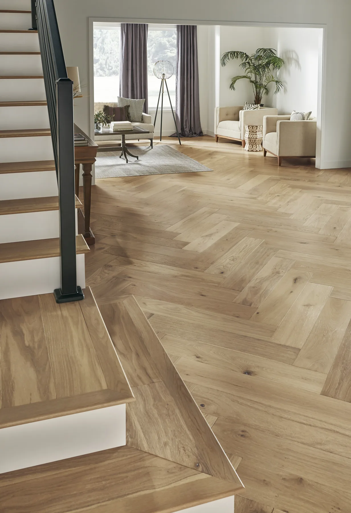 Light oak herringbone wood flooring meeting a staircase